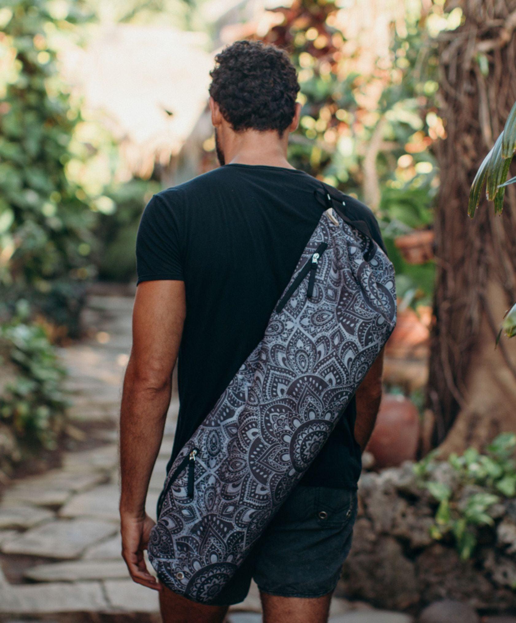 Person holding a patterned yoga mat bag outdoors